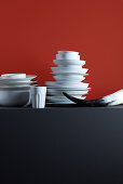 Stacked crockery, beaker and horn against red background