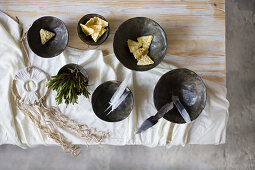 Feathers and crackers in black bowls on table