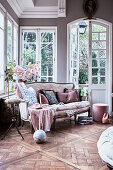 Antique sofa with cushions in front of roses in the lounge area