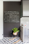 Schwarze Wand mit Kreidetafel und Klassiker-Schaukelstuhl neben Küchenschrank