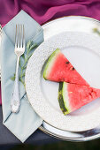 Fork on napkin next to watermelon wedges on plate