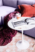 Cup and book on designer table on sofa with plaid in berry tones