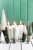 Adventsdeko: Miniatur-Tannenbäume aus Kunststoff und vier brennende Kerzen