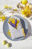 Spring flowers in folded napkin envelope decorating Easter table