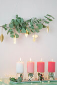 Eucalyptus branches with gold pendants above arrangement of candles