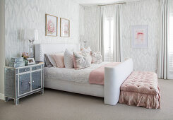 White-and-grey bedroom with pink accents and button-tufted bed bench