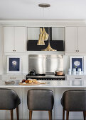 Bar stools at island counter with marble top in elegant kitchen