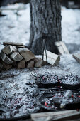 Cast iron pots covered with embers in camp fire in snow