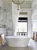 Freestanding bathtub in the bathroom with small marble tiles