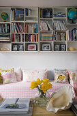 Shelves with many compartments on wall above sofa with romantic cushions and upholstery