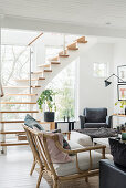 Rattan sofa and armchair in bright living room with staircase in background