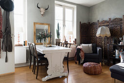 Dining table and chairs, armchair and screen in open-plan interior with pale grey walls