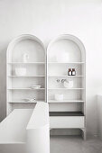 Two white shelves with arches and minimalist decoration