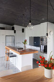 Barhocker an Kücheninsel mit Holzarbeitsplatte, weiße Einbauküche in offenem Wohnraum