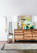 Sideboard with table lamp and works of art on white wall