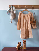 Nude-coloured linen dress on hooks in front of light blue wall