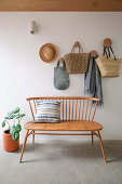 Classic transom bench in front of white wall with hooks and pockets