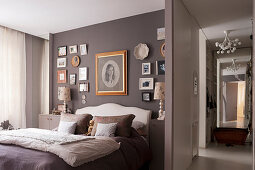 Gallery of photos on wall above double bed in taupe bedroom