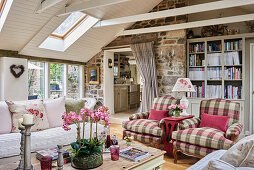 Tartan armchairs, bookcase and stone wall in attic living room