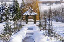 Frozen pond and pavilion in snowy garden