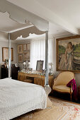 Frisierkommode, Sessel, darüber Gemälde im Schlafzimmer mit verspiegeltem Himmelbett