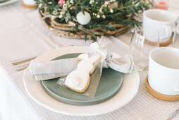 Place setting with bunny biscuit in gift bag on table set for Easter