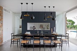 Black dining table and chairs in front of partition wall and next to open terrace doors