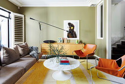 Cognac-colored leather chairs, classic table, sofa and sideboard in the living room with green walls