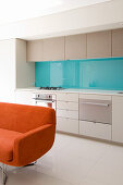 Orange sofa in front of modern open-plan kitchen