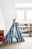 Blue and white striped tipi in front of a shelf in a white children's room