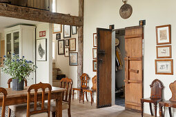 Alte chinesische Flügeltür aus Holz, Esstisch, Holzstühle und Zeichnungen an der Wand