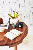 Notizbuch, Bücher und Blumen auf rundem Holztisch