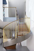Geschwungene Treppe mit goldenem Geländer im Wohnraum