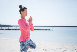 Frau macht Yoga-Übung am Meer