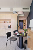 Black dining set in modern interior with open-plan kitchen
