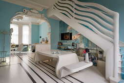 Designer furniture, sculptural stairway balustrade and sky-blue walls in extravagant maisonette apartment