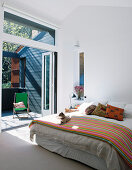 Doppelbett in hellem Schlafzimmer mit Balkon
