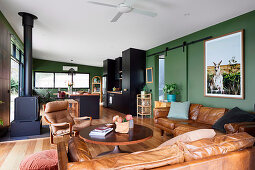 Open living room with green walls and leather furniture