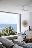 Wohnzimmer in Naturtönen mit Panoramafenster zum Meer