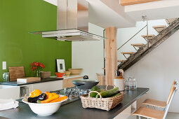 Island counter in open-plan kitchen below gallery in converted barn