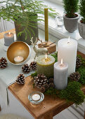 Festive arrangement of candles, pine cones and moss on table