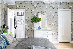 Double bed, white doors and lilac-patterned wallpaper in bedroom