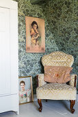 Oriental picture above old-fashioned armchair against vintage-style wallpaper