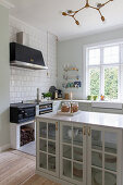 Glass-fronted cabinet in classic country-house kitchen with wood-fired cooker