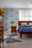 Schlafzimmer mit antikem Holzbett, Nachtschränkchen und nostalgischer Blumentapete