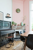 Piano next to open fireplace in dining room with pink wall