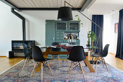 Black shell chairs around dining table in front of old dresser painted petrol blue
