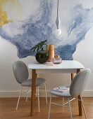 Upholstered chairs and table in front of watercolour-effect panel on wall