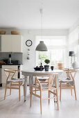 Designer chairs with fur seat cushions around traditional table in kitchen