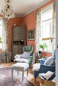 Two armchairs flanking window in living room with salmon-pink walls